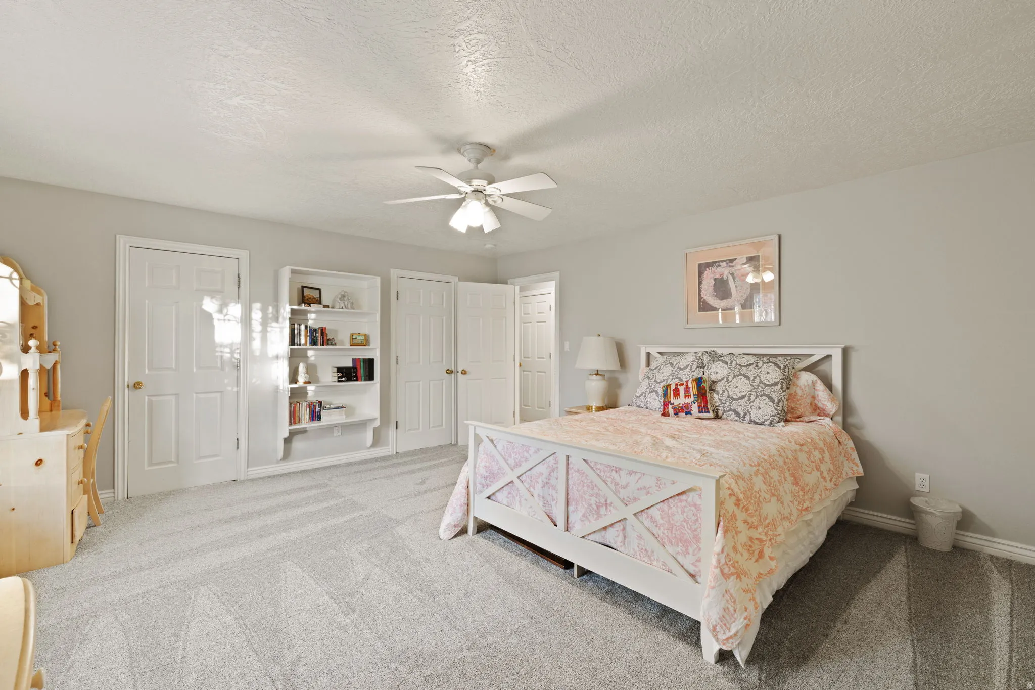 Carpeted interior room featuring light gray walls and a white ceiling fan