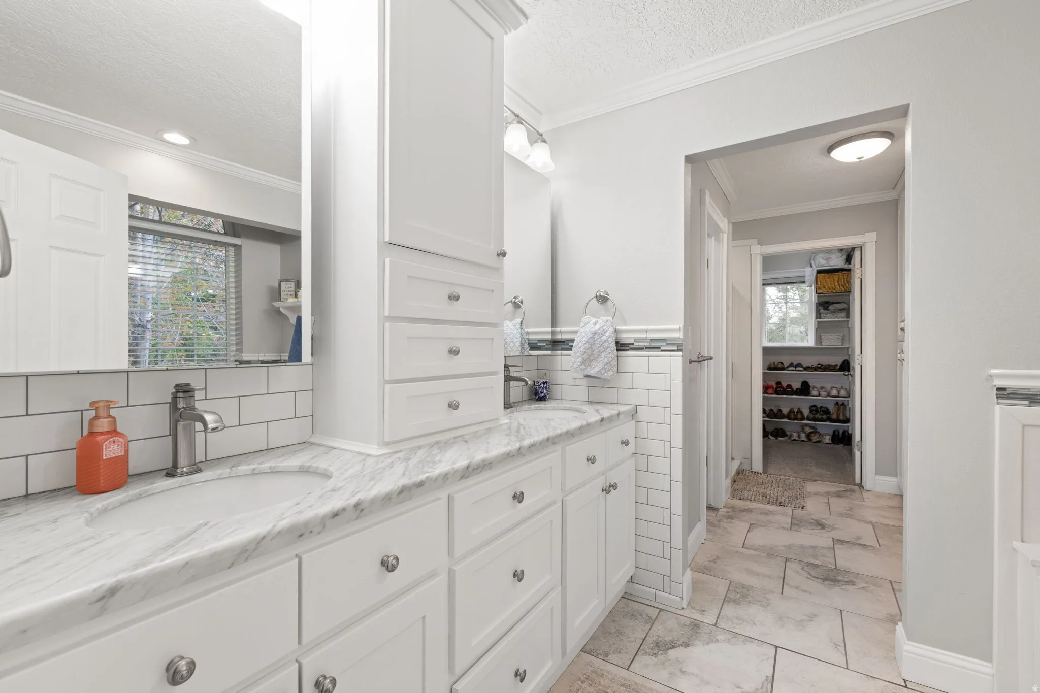 Primary bathroom with double vanity,  undermount sinks, white shaker-style cabinetry and heated tile flooring
