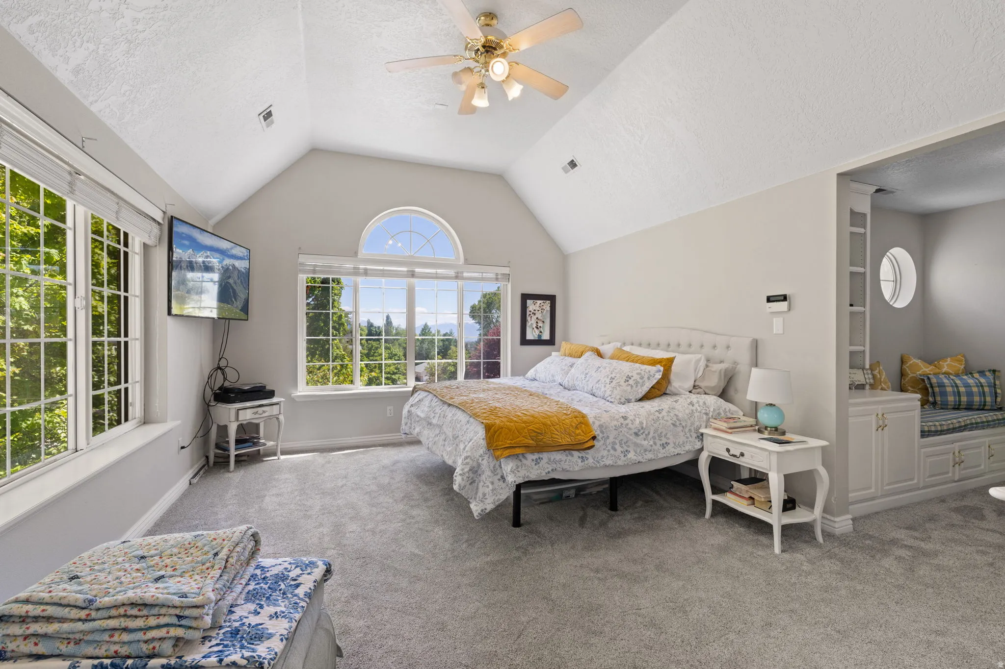 Primary bedroom with vaulted ceiling, large paneled windows, and a ceiling fan
