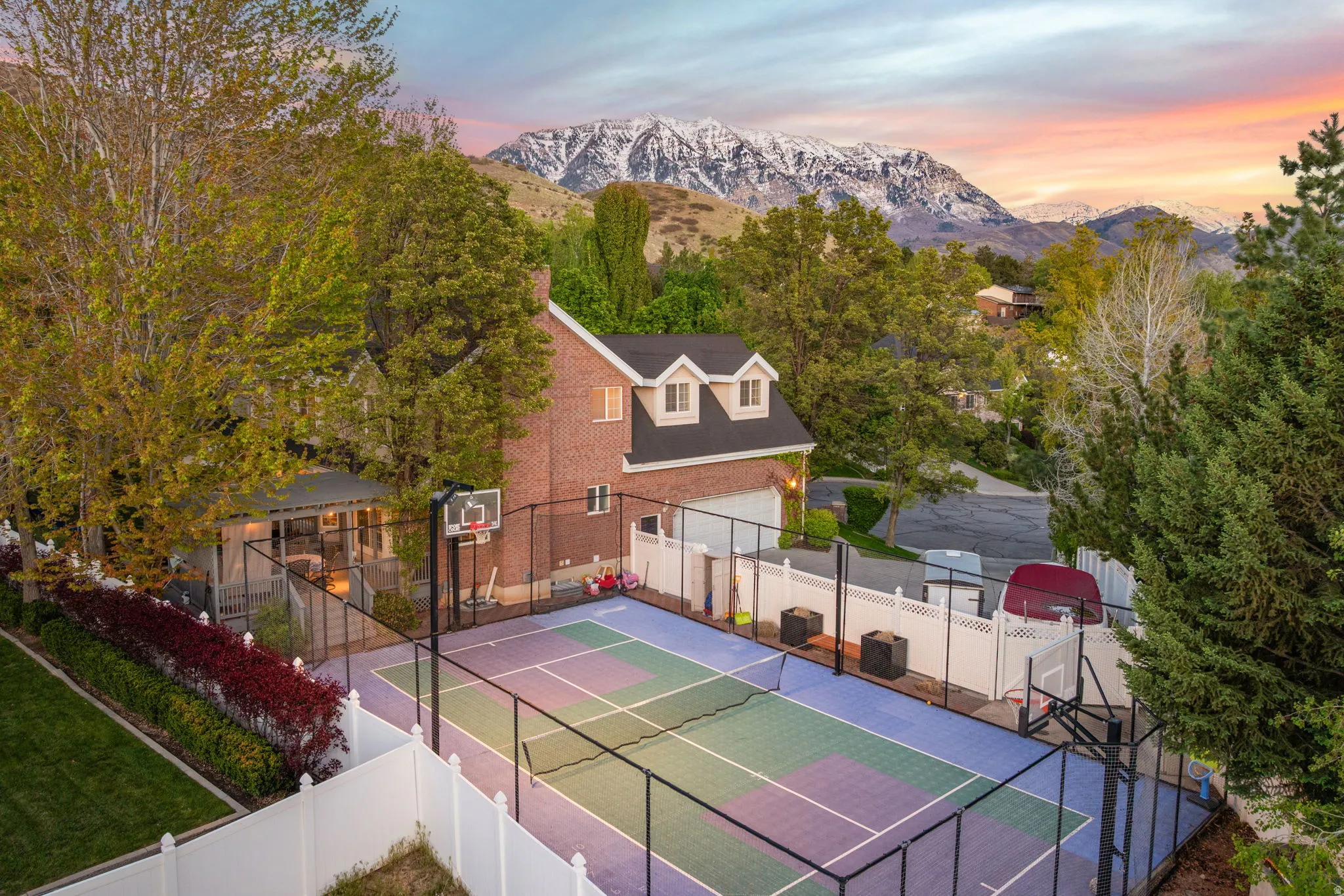 Brick residence featuring a multi-sport court with surrounding fencing