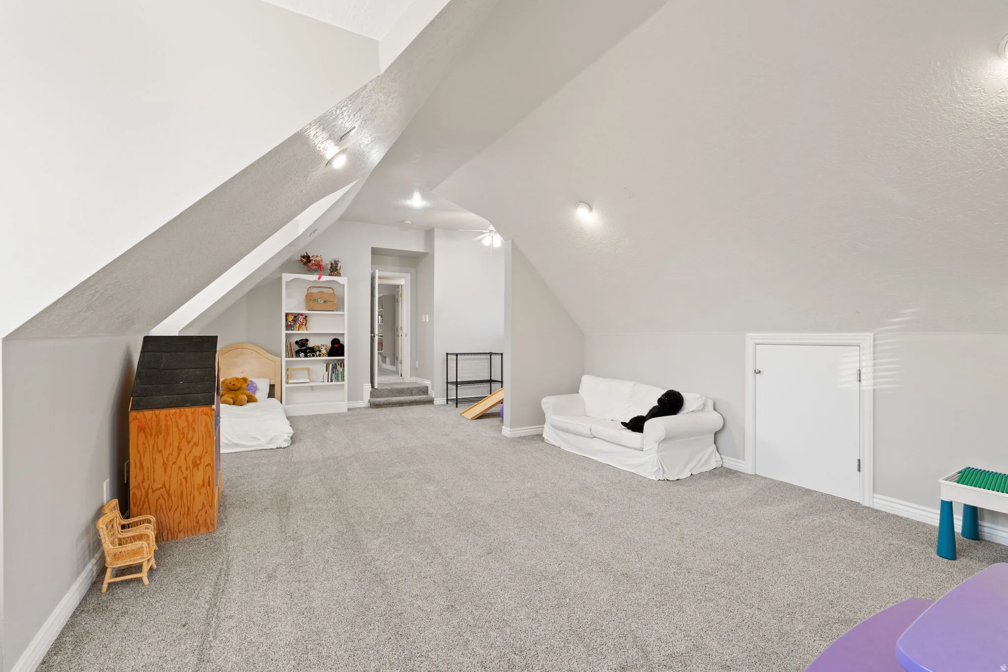 Expansive loft featuring light gray carpet flooring and a vaulted ceiling