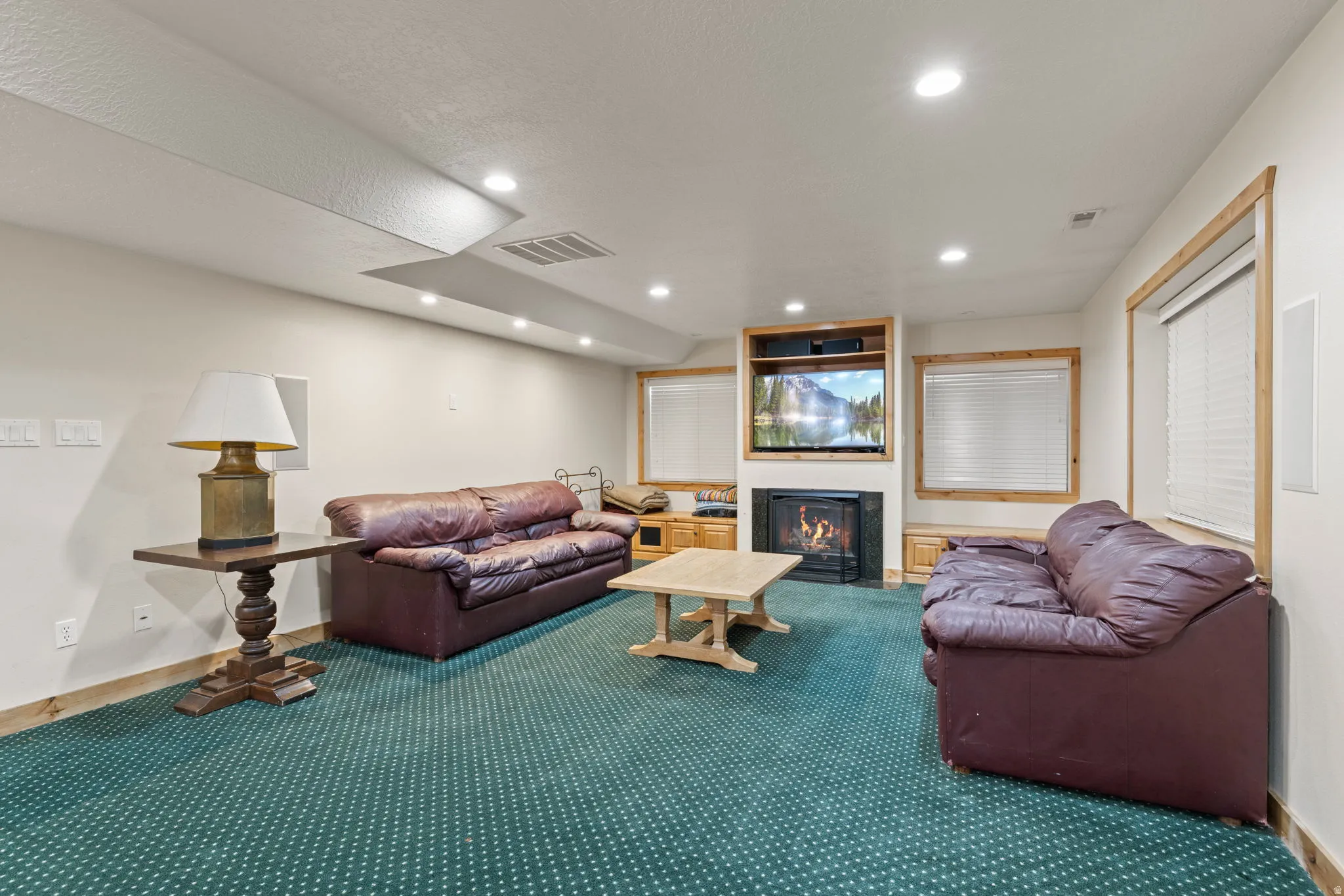 Spacious living area featuring recessed lighting, a built-in entertainment center with a fireplace, and wood-trimmed windows with blinds