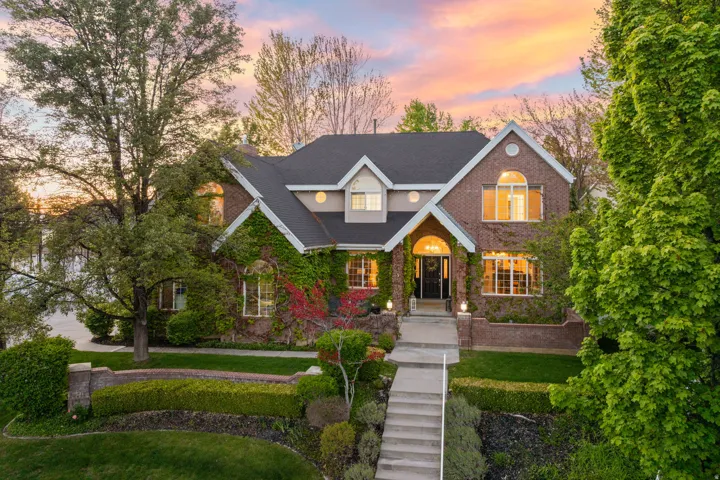Brick exterior featuring a gabled roofline, arched entry, prominent windows, and mature climbing ivy