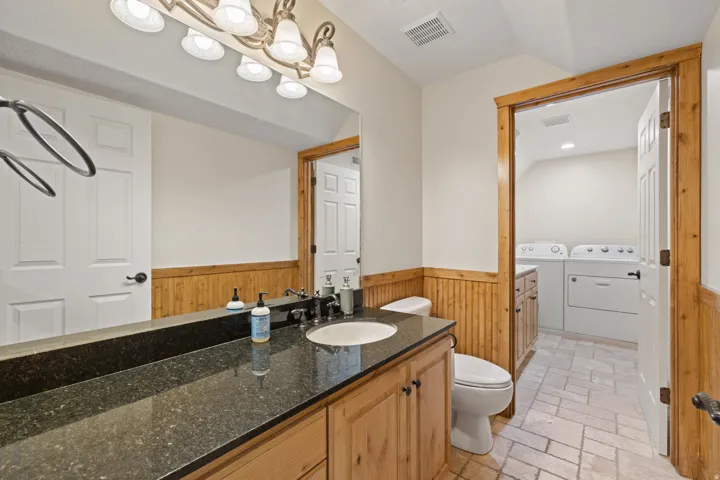 Bathroom featuring a wood-finish vanity with granite countertop and an undermount sink