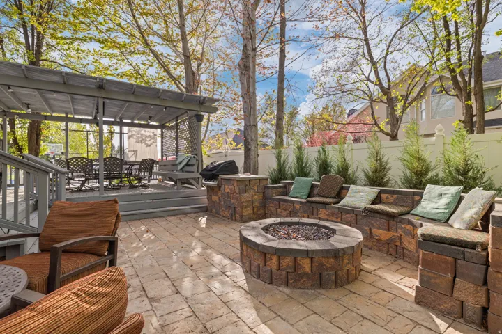 Expansive paver patio featuring a built-in fire pit with a stone surround