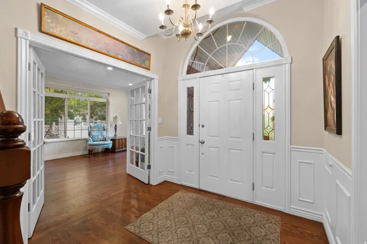 Grand entryway featuring French double doors, an arched transom window, and decorative leaded glass sidelights