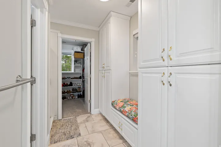 Primary bathroom featuring built-in white cabinetry, a built-in bench, and heated tile flooring