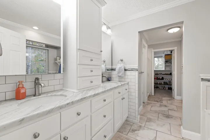 Primary bathroom with double vanity,  undermount sinks, white shaker-style cabinetry and heated tile flooring