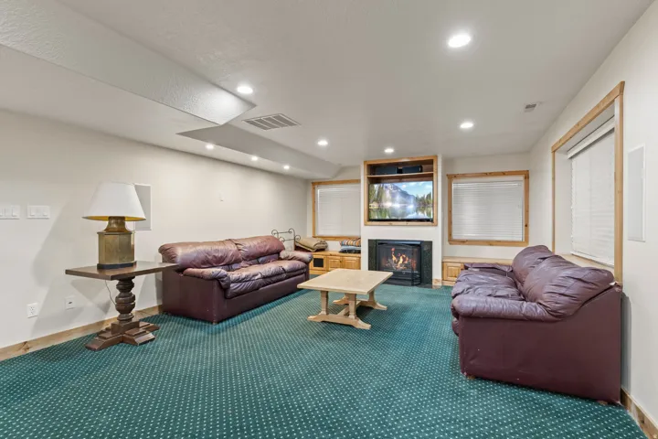 Spacious living area featuring recessed lighting, a built-in entertainment center with a fireplace, and wood-trimmed windows with blinds