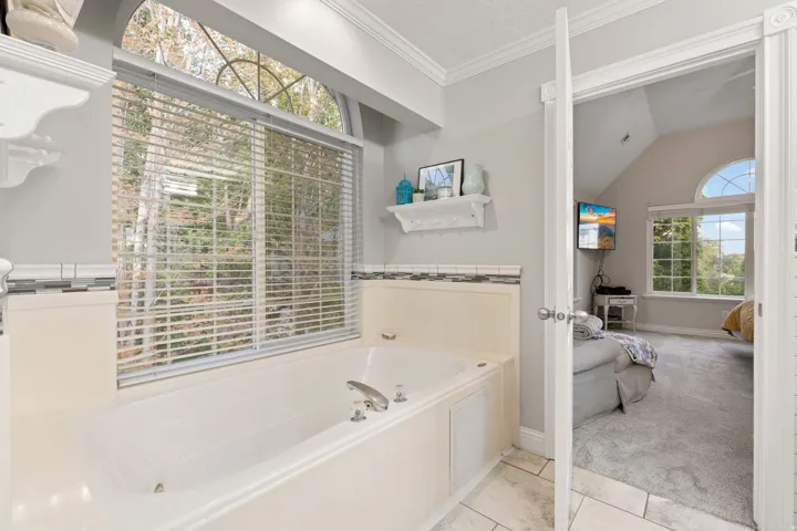 Primary bathroom with soaking tub set against a large window with arched transom