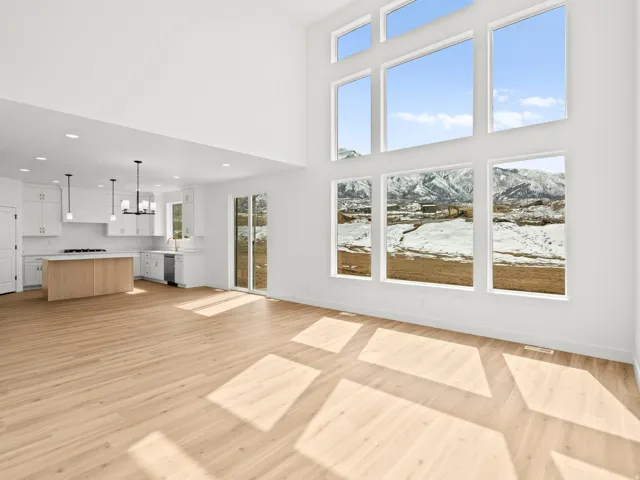 Two-story living area with expansive window walls, light wood-finish flooring, and white walls