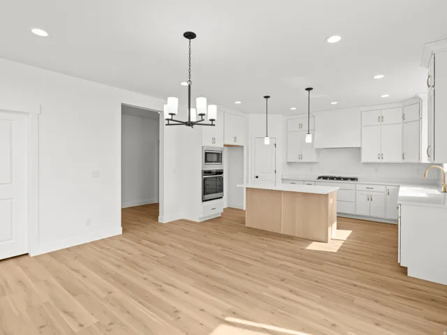 Open-concept kitchen with white cabinetry and light wood-finish flooring