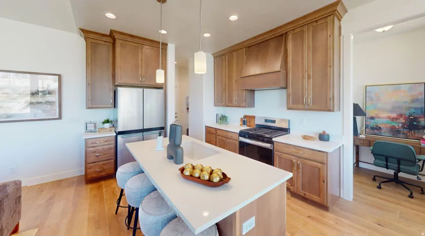 Kitchen featuring wood-finish cabinetry, stainless steel appliances, a center island with countertop seating, and recessed lighting