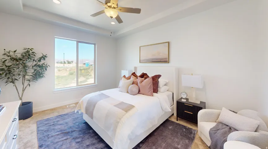 Spacious bedroom featuring a tray ceiling, recessed lighting, and a ceiling fan