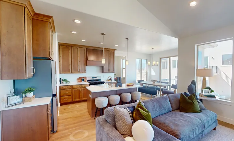 Open-concept living space featuring wood-finish flooring, a kitchen island with seating, recessed lighting, and large windows