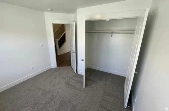 Carpeted room with a built-in closet featuring bi-fold doors and a hanging rod