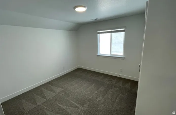 Carpeted room with a single window featuring a blind
