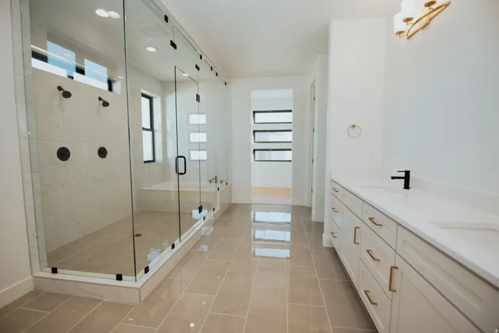 Spacious bathroom featuring a large glass-enclosed shower with multiple showerheads, a built-in bench, and a standalone soaking tub