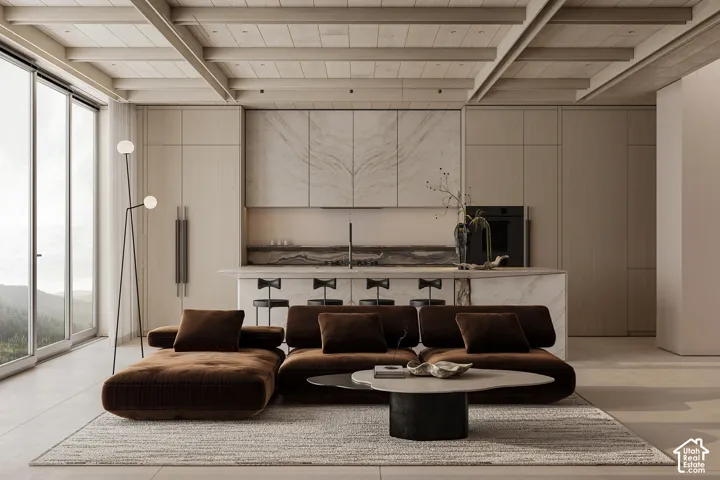 Spacious open-concept interior featuring large format floor tiles, exposed beam ceiling, full-height sliding glass doors, a kitchen island with integrated seating, and custom cabinetry with stone accents
