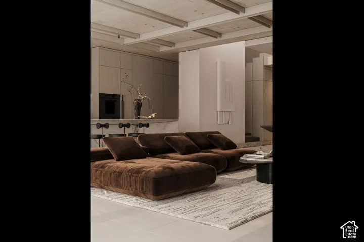Open-concept living area featuring a neutral color palette, integrated kitchen cabinetry, built-in oven, and a marble-top island with seating