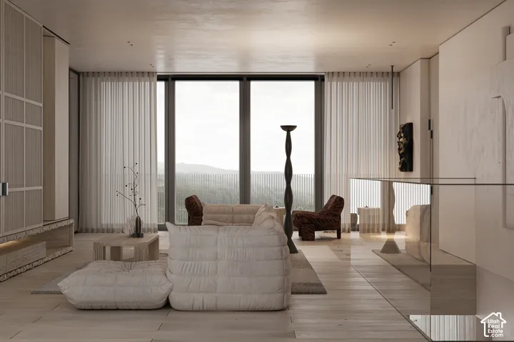 Spacious living area featuring expansive floor-to-ceiling windows, light wood-finish flooring, and a glass railing