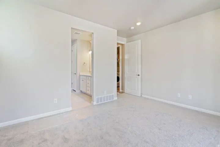 Neutral-toned room featuring light gray carpeting and white baseboards