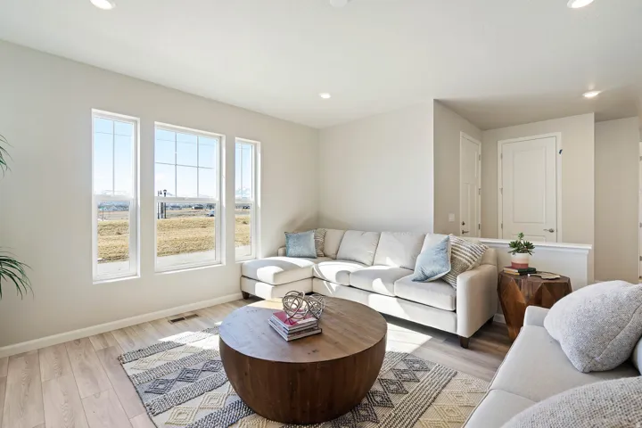 Bright living area featuring wood-finish flooring, recessed lighting, and three tall windows