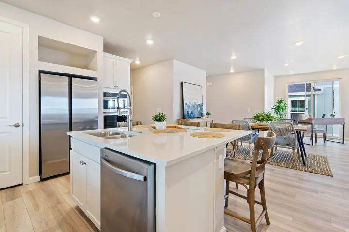 Kitchen island featuring a stainless steel sink with a high-arc faucet and a quartz countertop