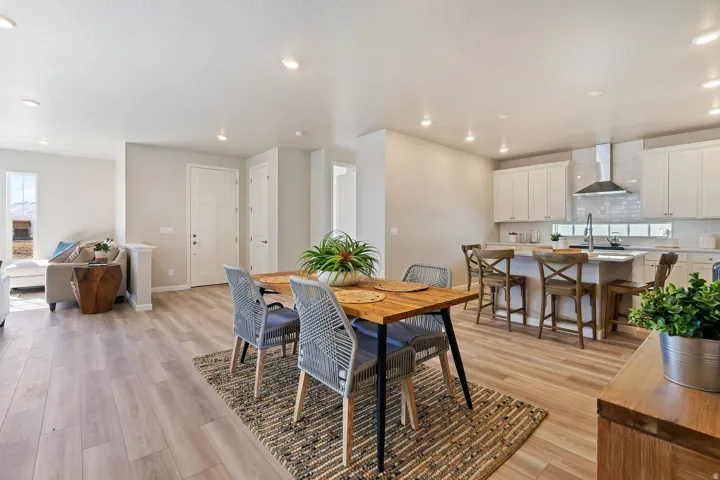 Open-concept dining area featuring wood-finish flooring, recessed lighting, and a textured area rug