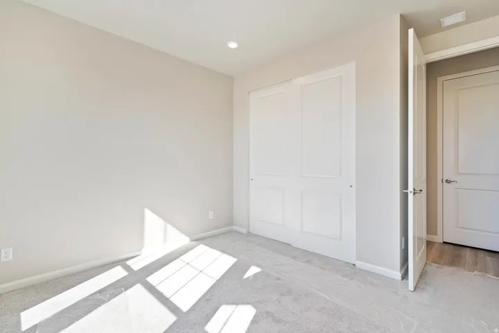 Interior room featuring light-toned walls, recessed lighting, and soft gray carpeting