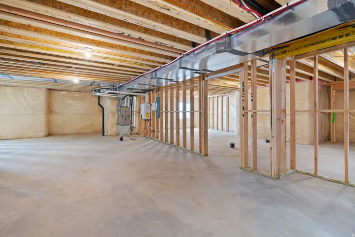 Unfinished basement space featuring exposed wooden joists and framing
