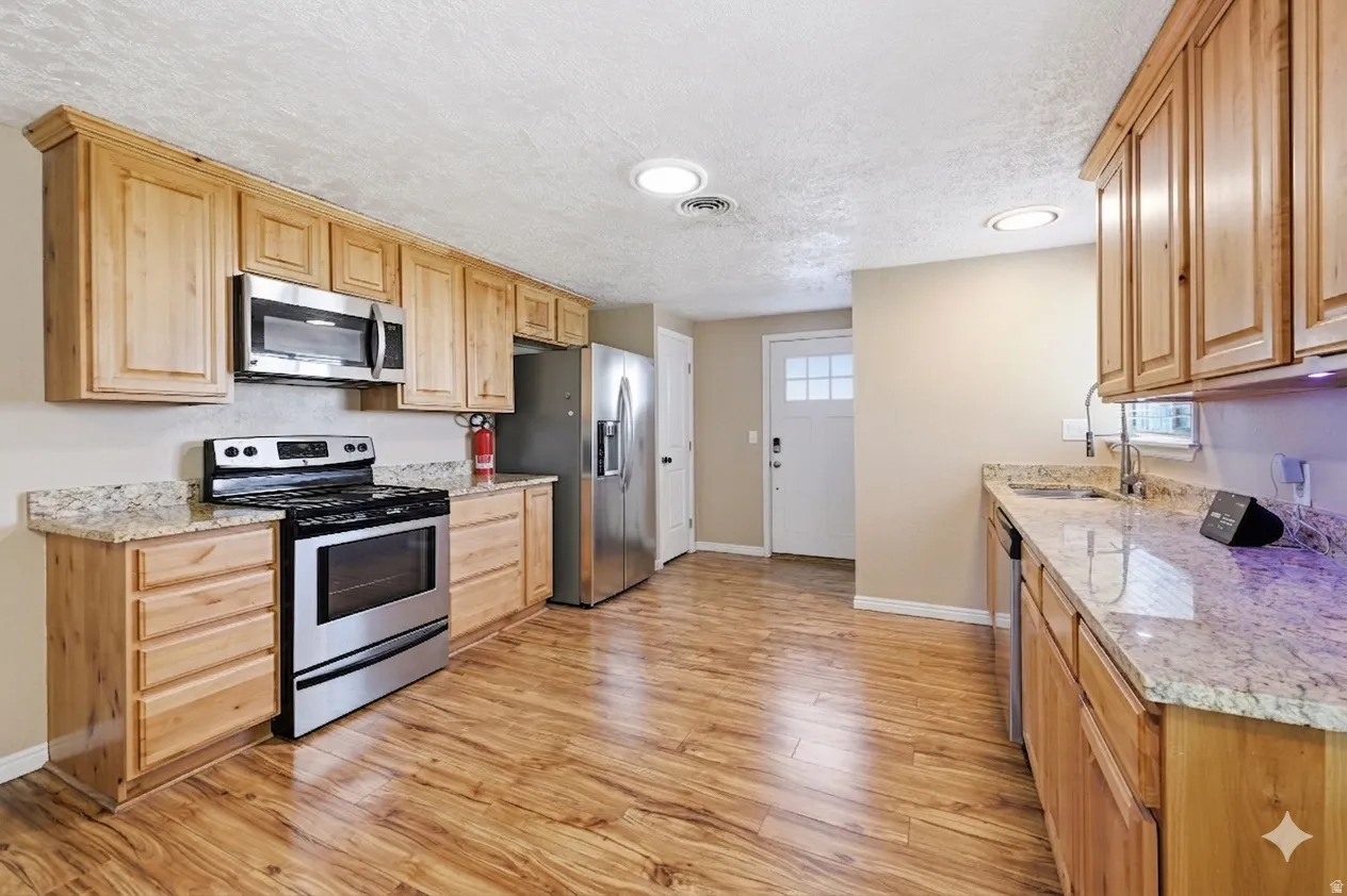 Kitchen featuring wood-finish flooring and light-toned cabinetry