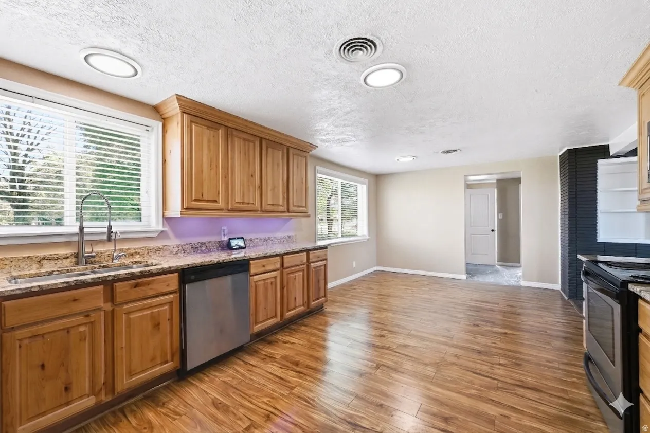 Kitchen featuring wood-finish flooring, custom wood cabinetry, and granite countertops