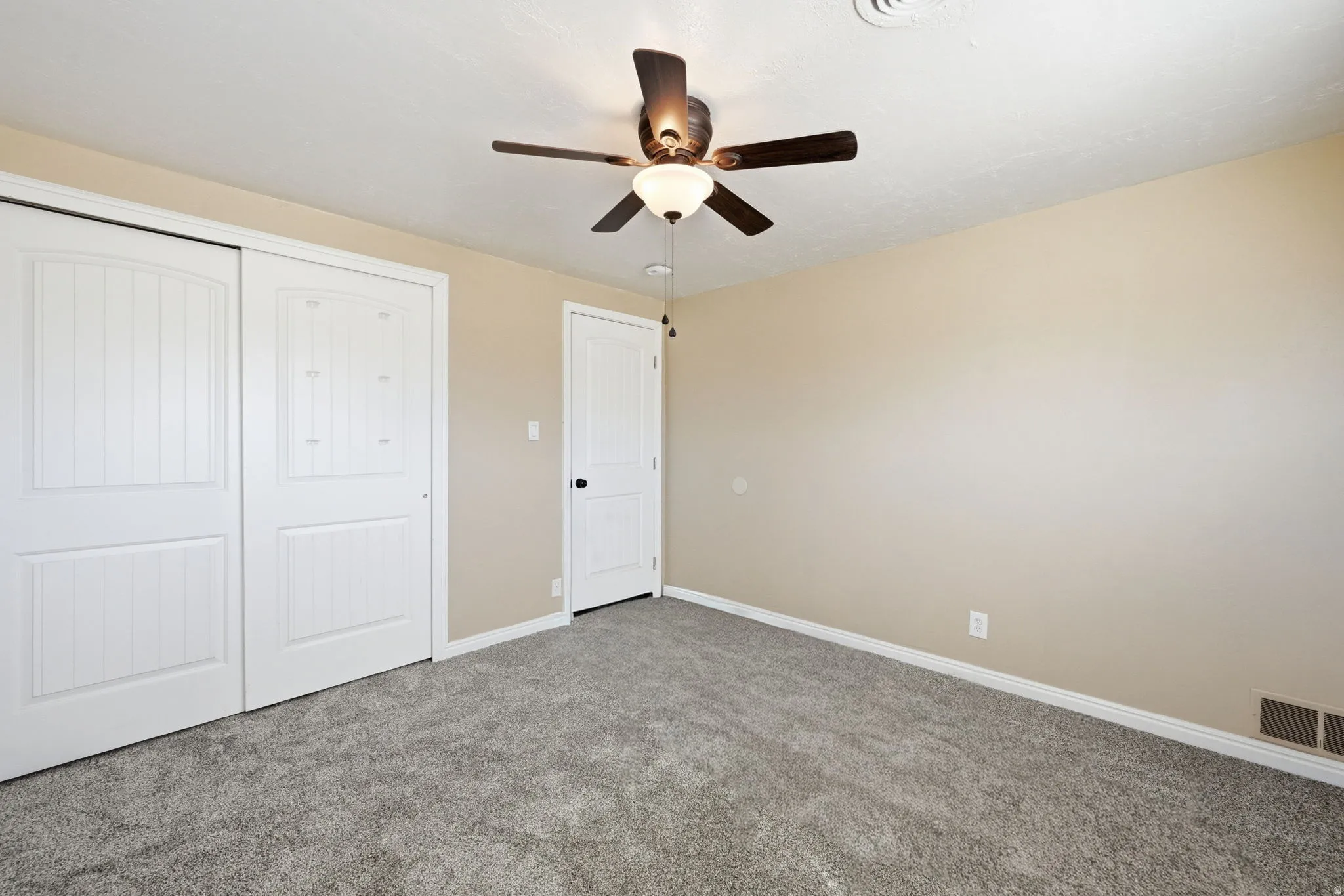 Bedroom featuring light tan walls, gray carpeting, and white baseboards