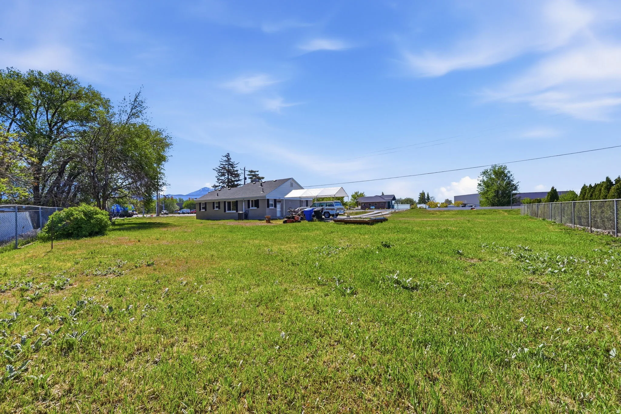 Expansive grassy yard with a chain-link perimeter fence and mature trees