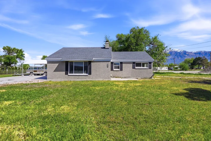 Gray brick exterior featuring black shutters and a light gray shingle roof