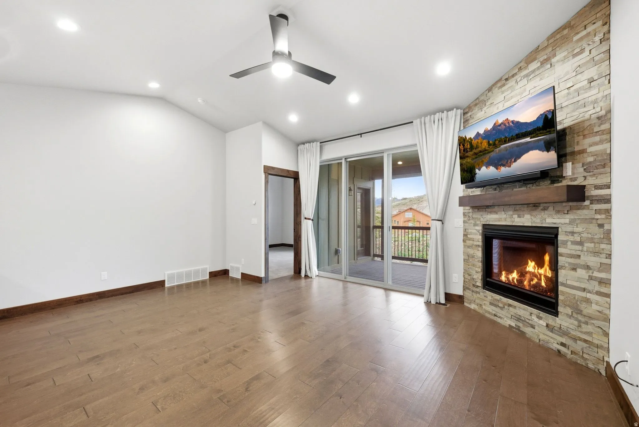 Living space featuring a stone-clad fireplace with a wood mantel, wood-finish flooring, and recessed lighting
