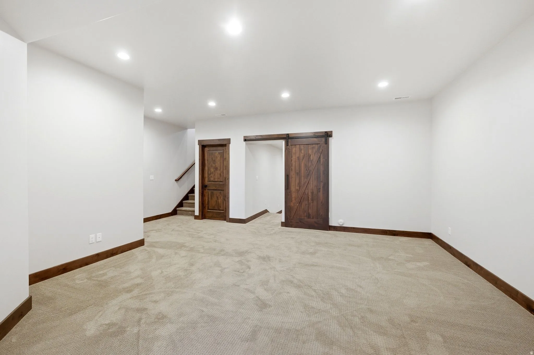 Spacious room featuring neutral carpet flooring, recessed lighting, and white walls