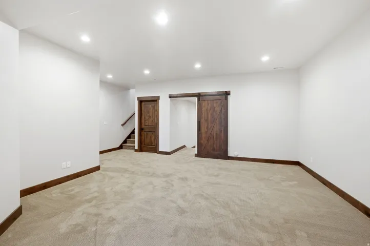 Spacious room featuring neutral carpet flooring, recessed lighting, and white walls