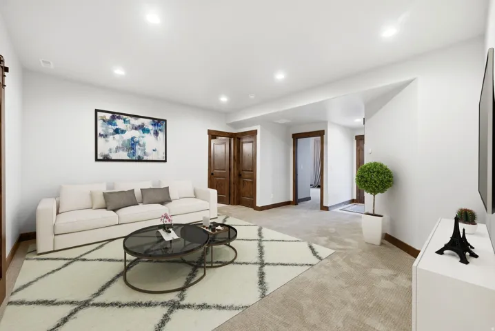 Spacious living area featuring recessed lighting, light-toned carpeting, white walls, and dark wood-finish trim and doors