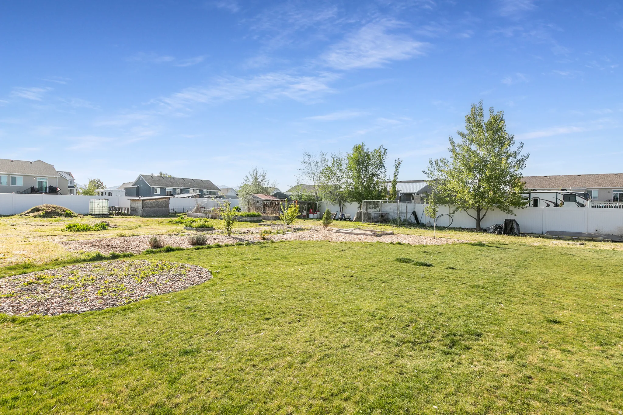 Expansive backyard featuring a large green lawn, perimeter fencing, and mature trees