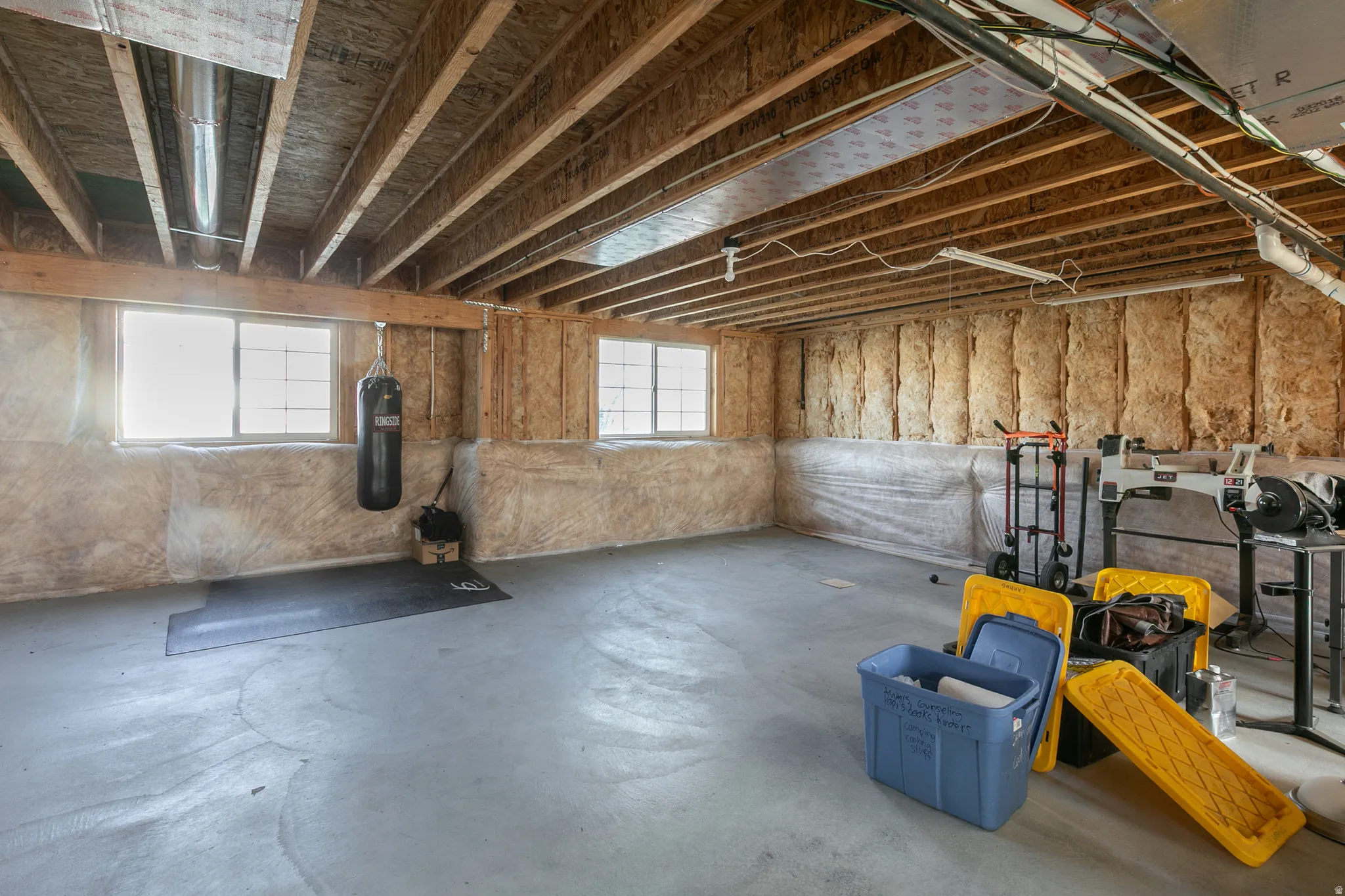 Unfinished lower level featuring exposed wood joists, structural wood beams, and a concrete floor