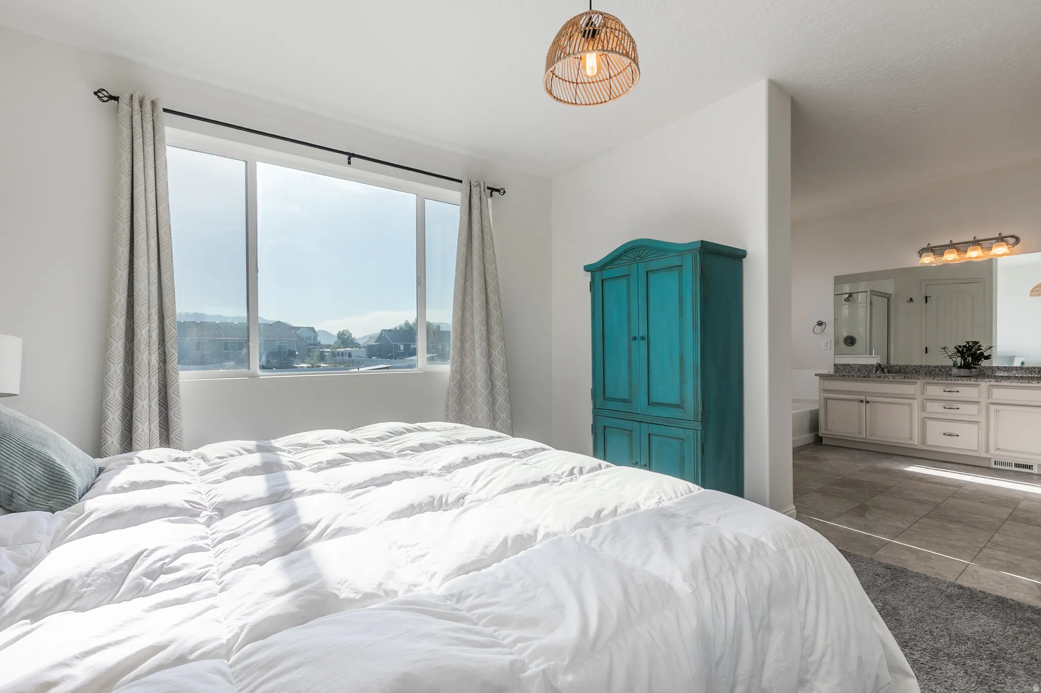 Bedroom featuring a large window with white trim, a woven pendant light fixture, and carpet flooring