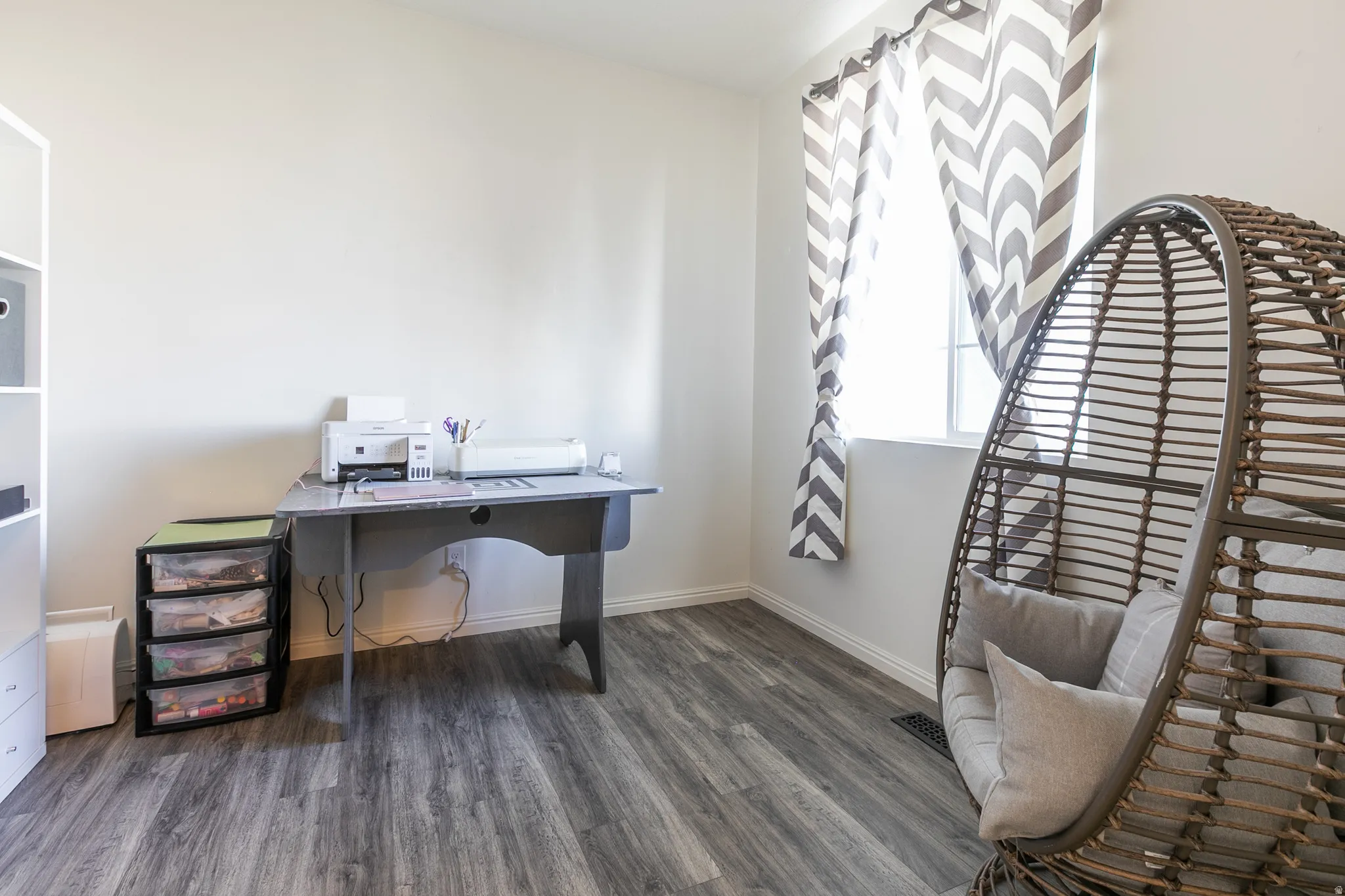 Room featuring wood-finish flooring, white baseboards, and a window with white trim