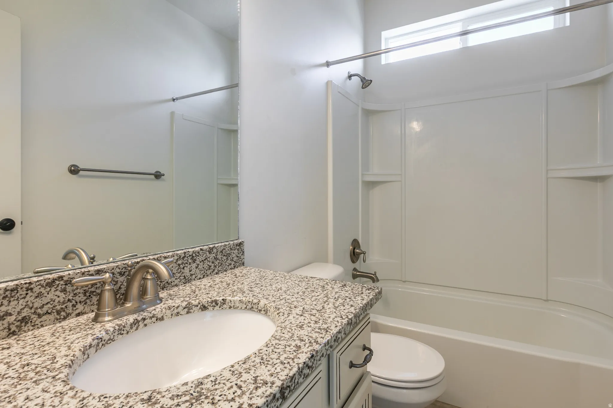 Bathroom vanity featuring a speckled countertop with an undermount sink and brushed nickel faucet