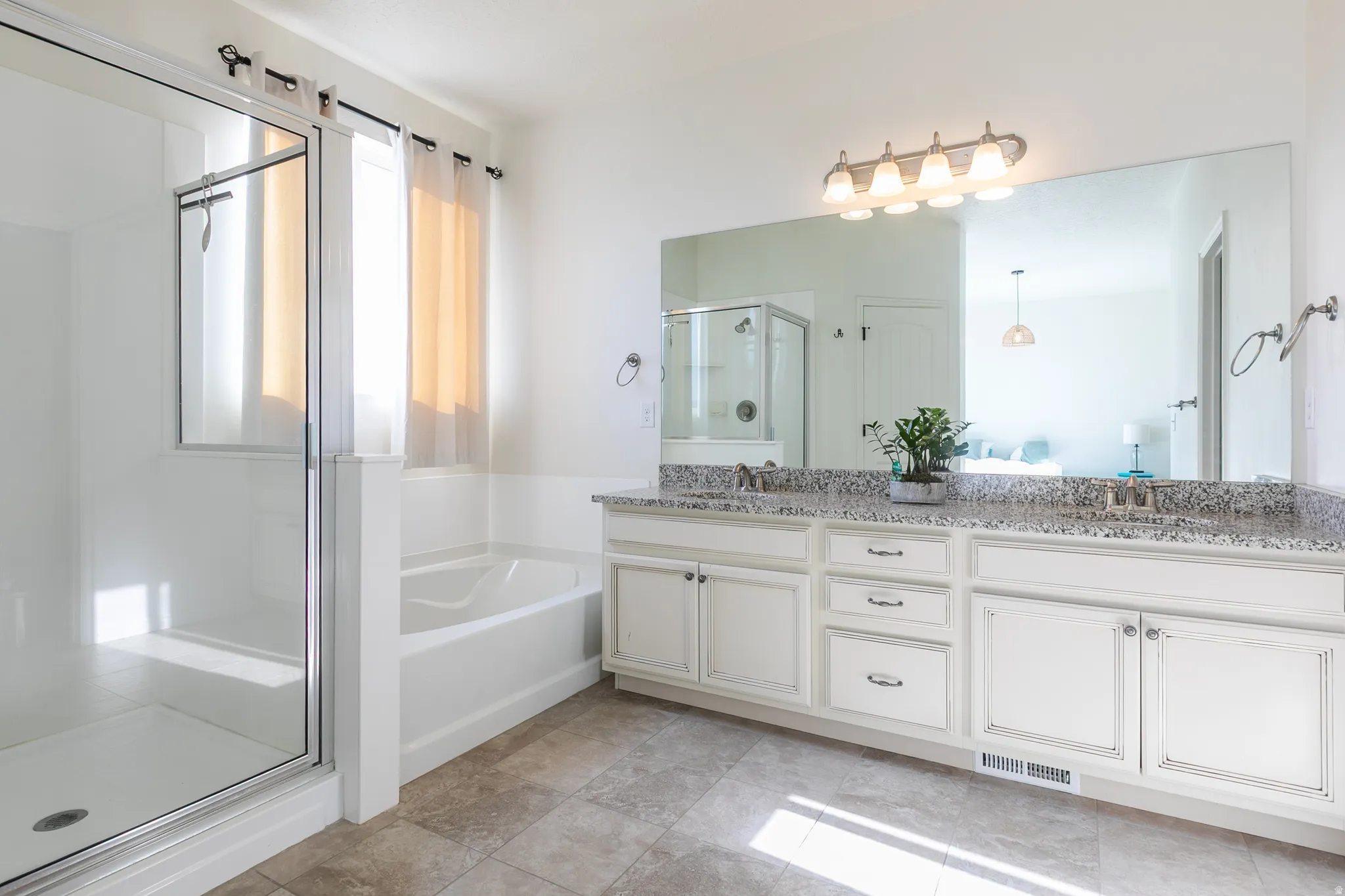 Bathroom featuring a dual vanity with granite-finish countertop, undermount sinks, and white cabinetry