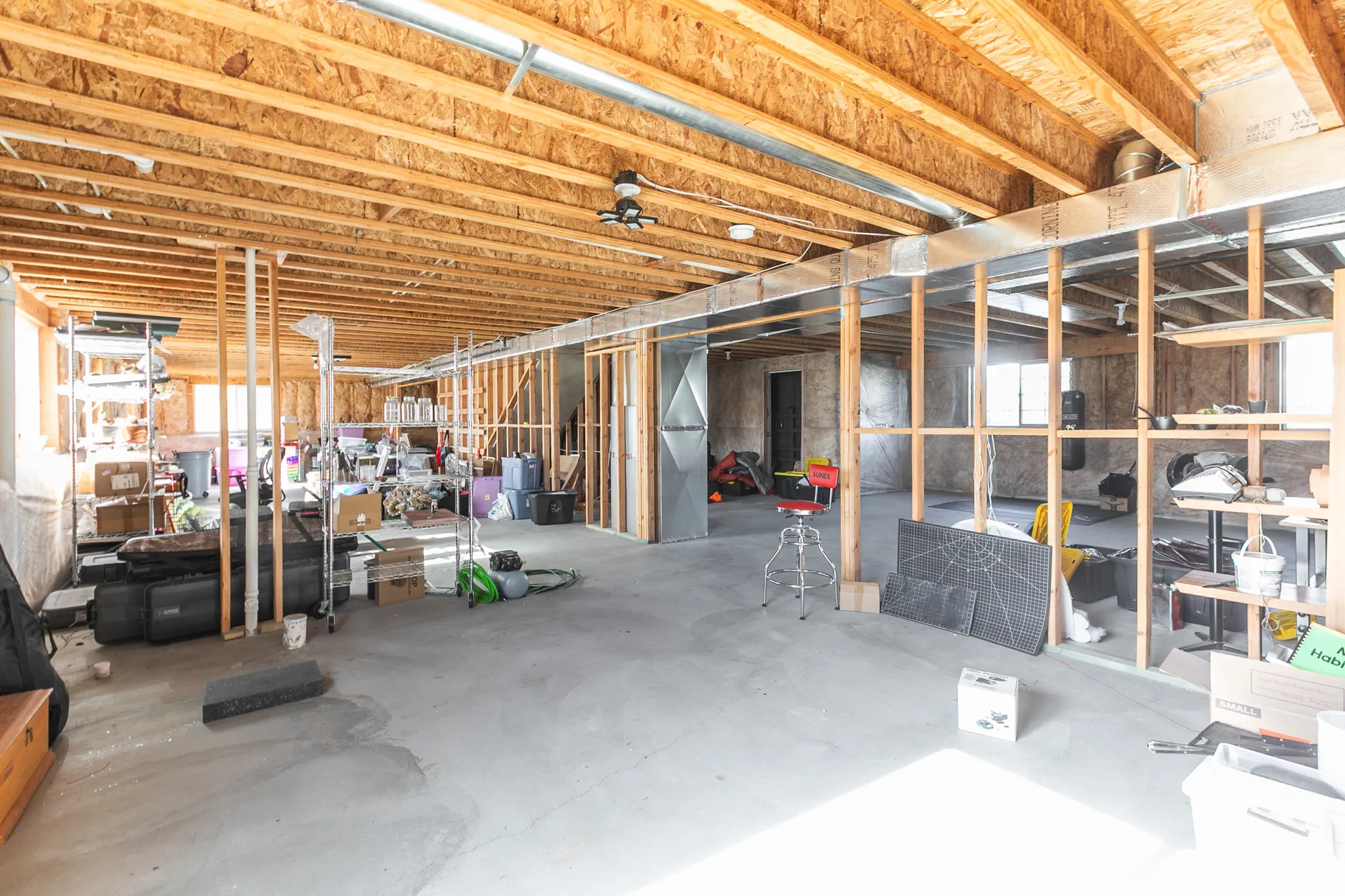 Unfinished basement with exposed ceiling joists and concrete flooring