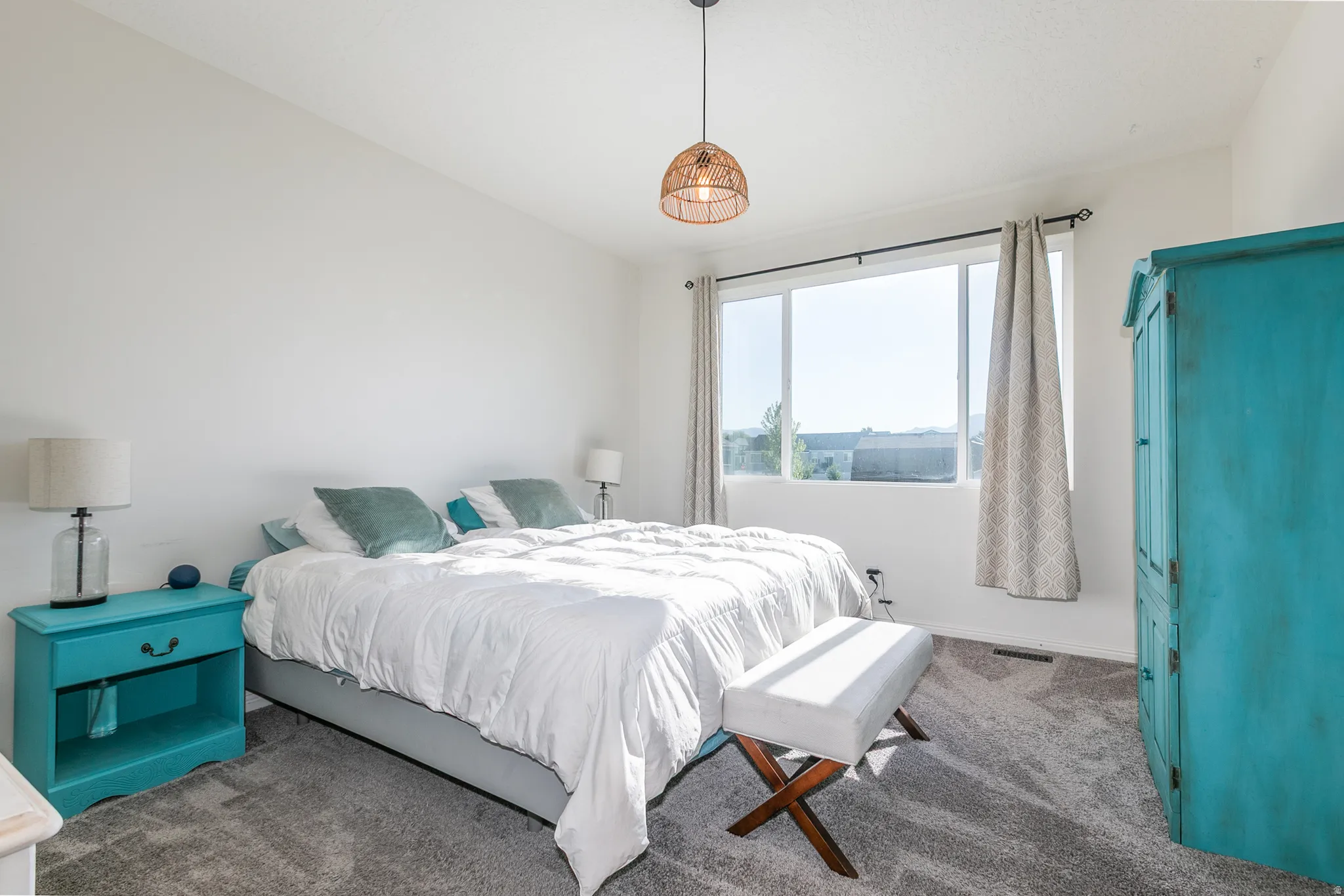 Carpeted room featuring a large window, white walls, and a woven pendant light fixture