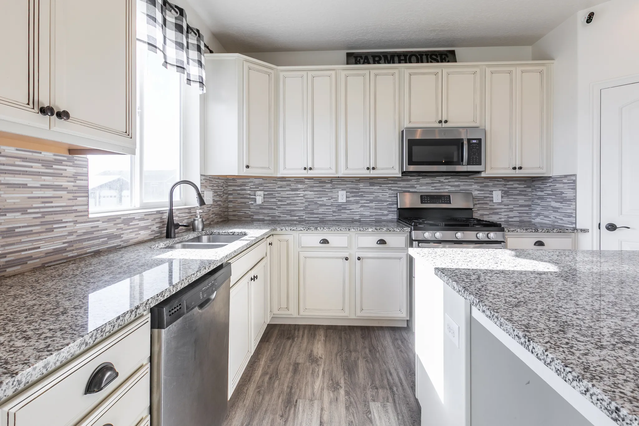 Kitchen featuring light-finish cabinetry, speckled countertops, and a mosaic tile backsplash