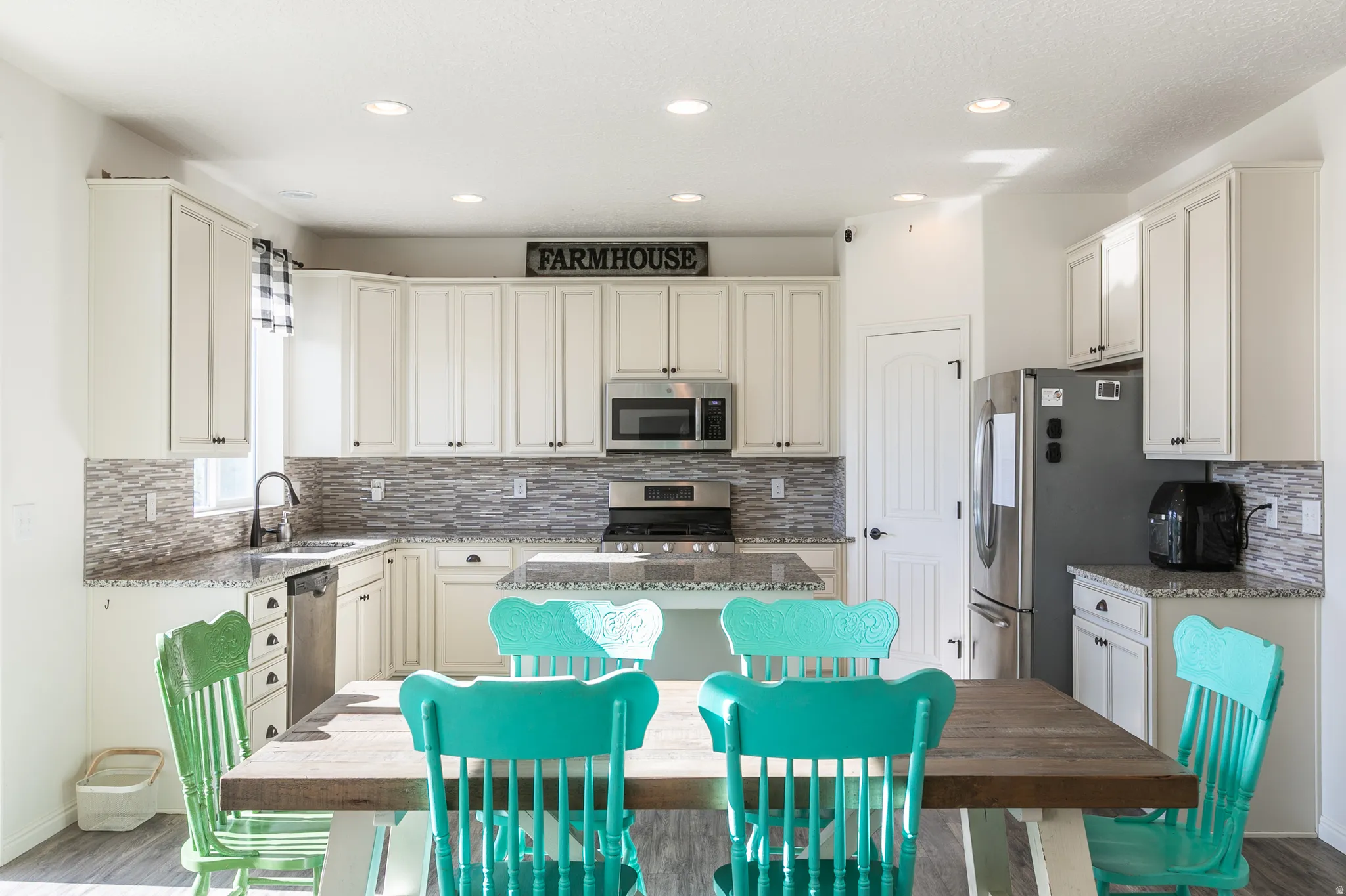 Spacious kitchen featuring white cabinetry, stainless steel appliances, granite countertops, and a mosaic tile backsplash